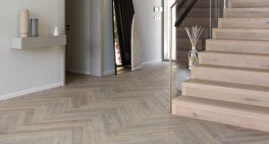 An entryway with premium flooring materials, a staircase, a wall shelf, and other decorations of a Golf Place Villa. 