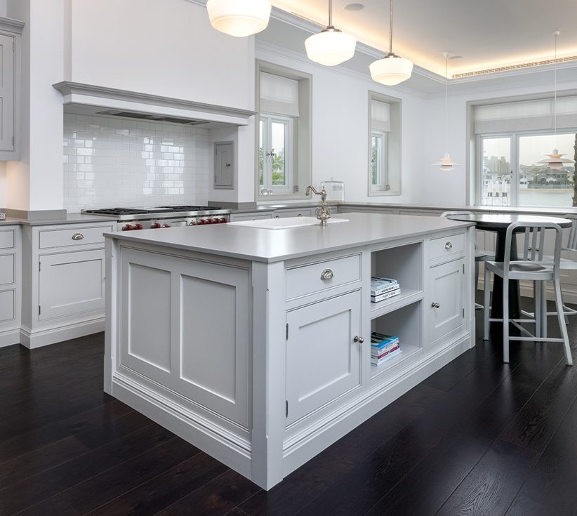 A white-themed kitchen inside a private Fond Villa in Palm Jumeirah, Dubai, with furniture and dark wood flooring
