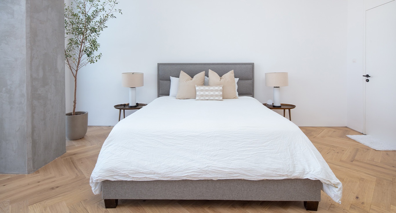 At KOA Canvas Apartment in Al Barari, Dubai, the minimalist bedroom design is enhanced with parquet floors by Nordic Homeworx.