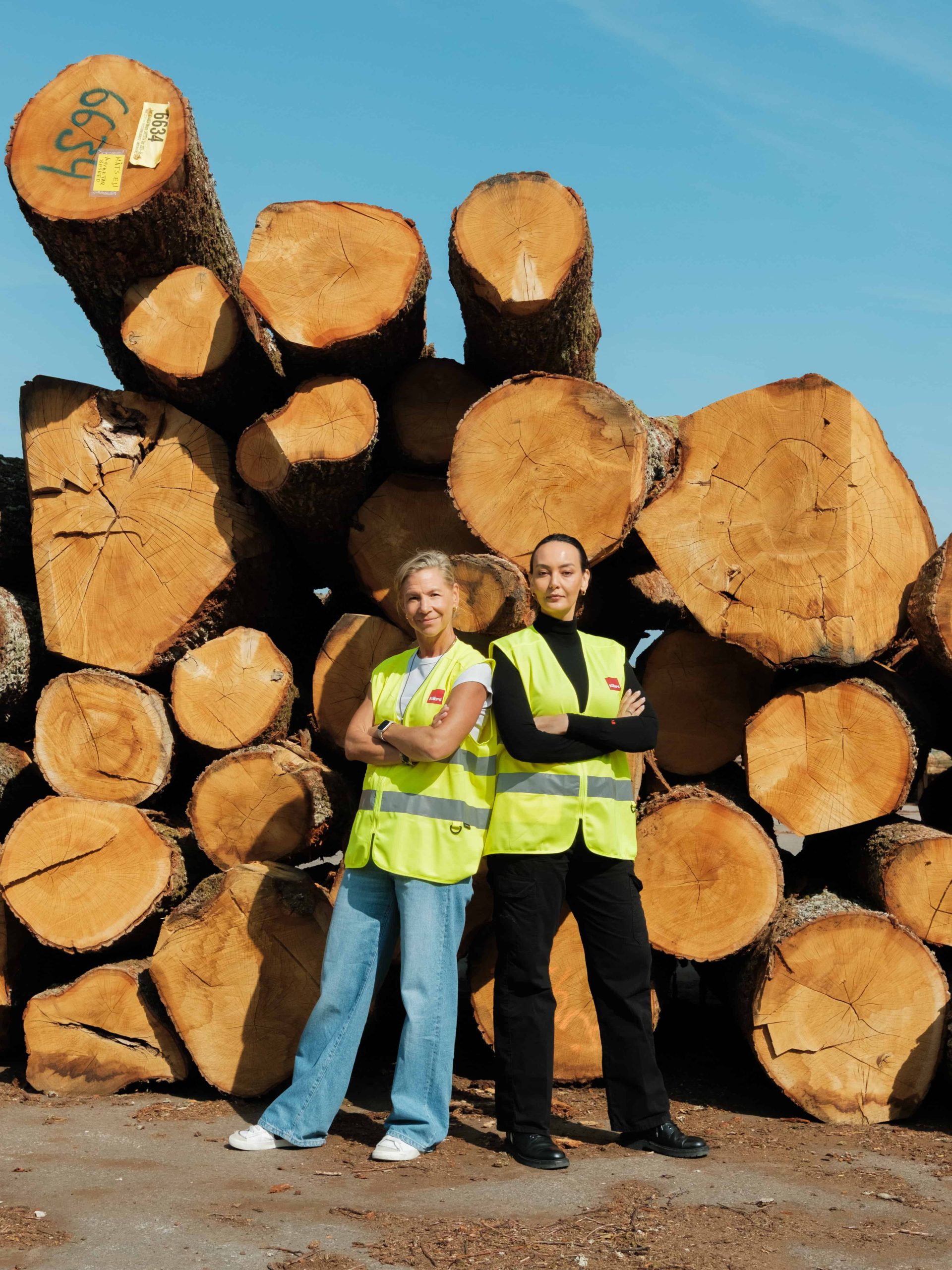 Pauline Madani and Rabah Saeid in front of logs at the Kährs factory