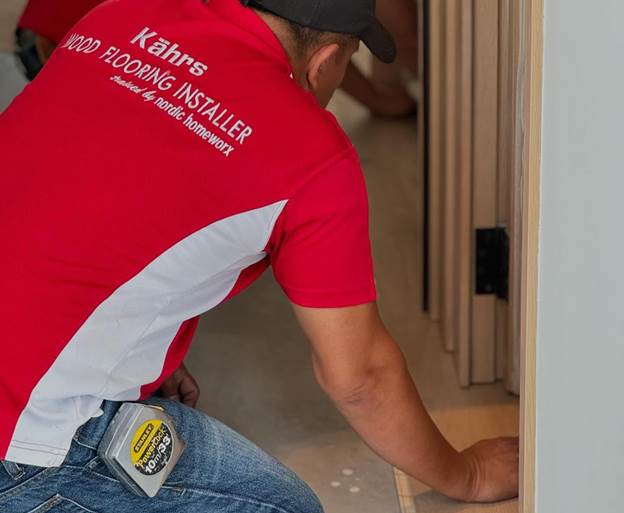 Installer fitting wood flooring, highlighting professional    workmanship across different wood flooring types.