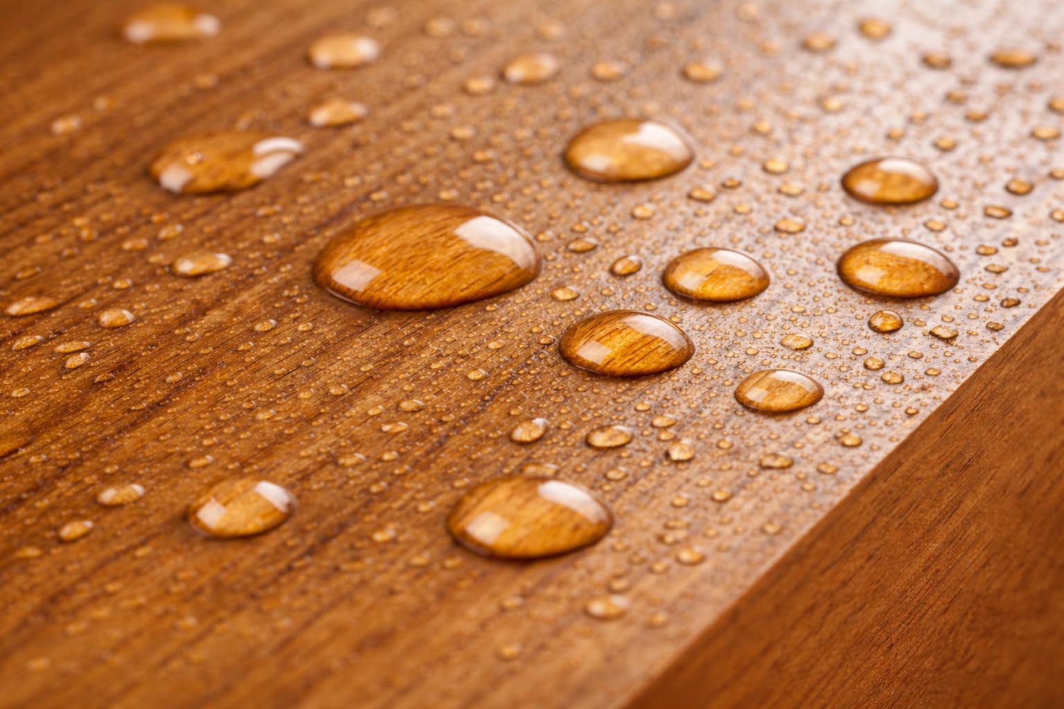 A close-up of the teak wood surface with water droplets, highlighting its water-resistant properties.