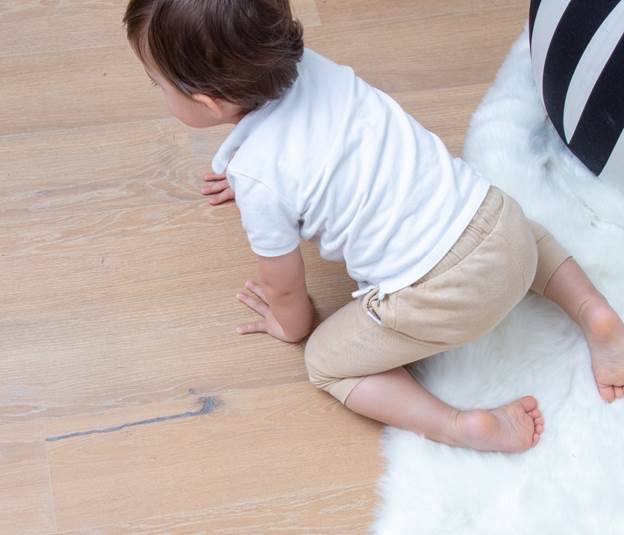 Toddler on the floor, showing the natural comfort and family use of    different wood flooring types.