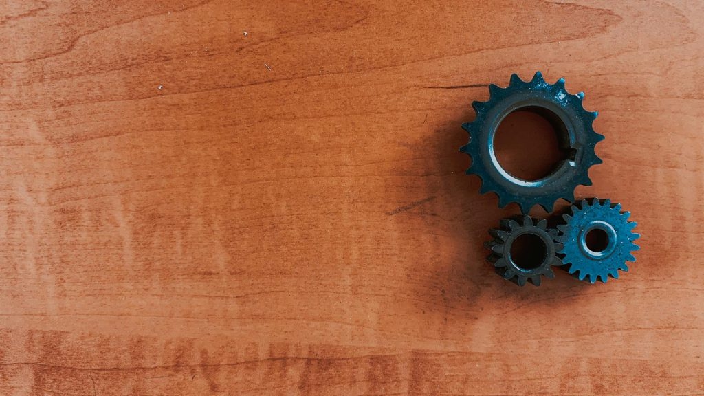  A plank of engineered wood with three black metal gears on top of it.