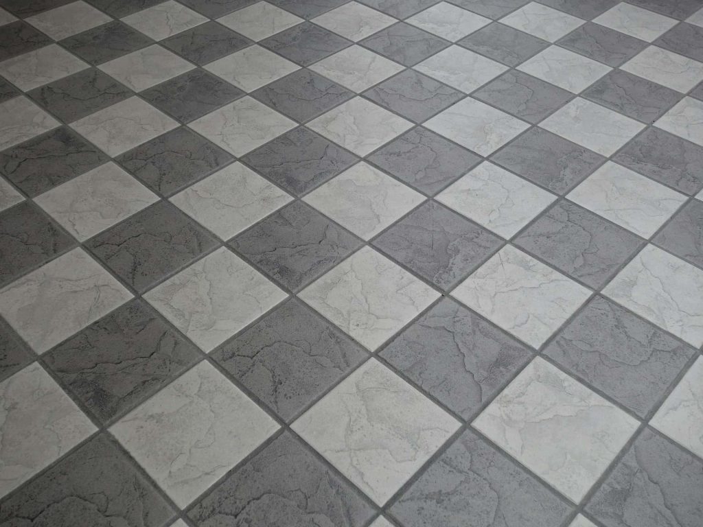 Top view of the floor with white and grey ceramic tiles with grey grout.