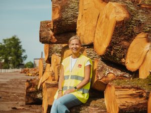 Pauline Madani, Founder and Managing Director of Nordic Homeworx, sitting on premium oak logs at the Kährs factory.